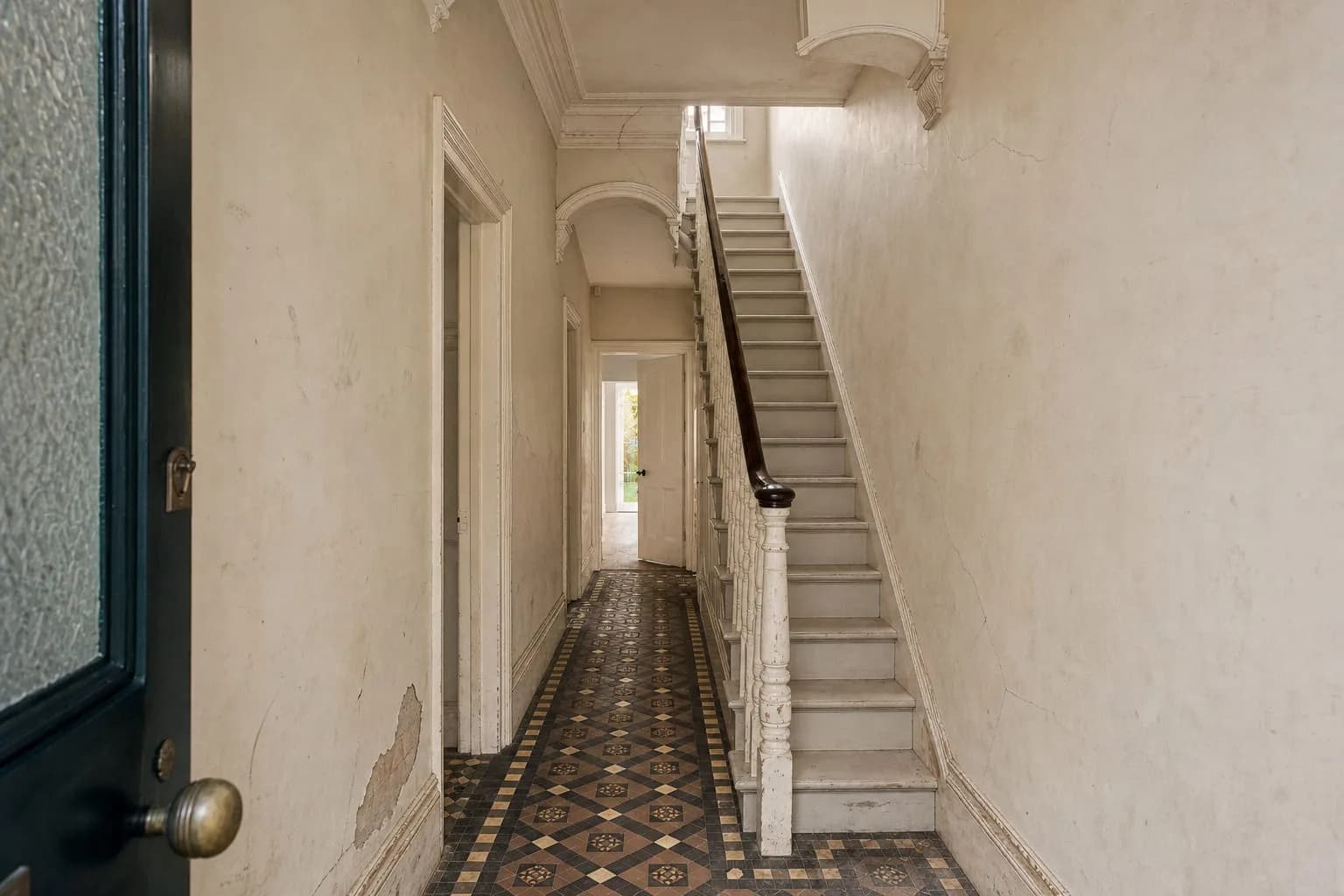 Before: the same hallway with cracked, stained walls and chipped woodwork